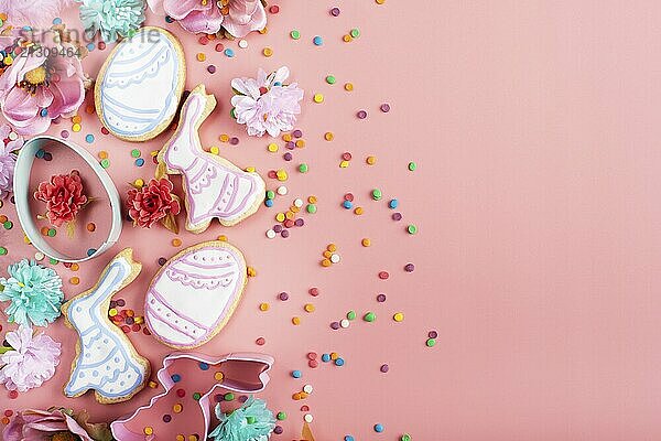 Sugar sprinkles  Cookie cutters  Easter frosted cookies in shape of egg and rabbit on pink background. Flat lay mockup with copy space