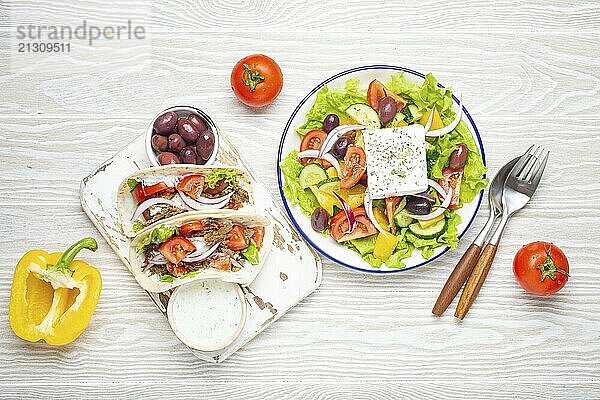 Traditional Greek Food: Greek Salad  Gyros with meat and vegetables  Tzatziki sauce  Olives on White rustic wooden table background top view. Cuisine of Greece  food photography  food photography