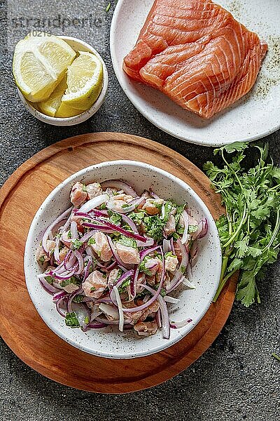 Food  Food  CHILEAN SALMON CEVICHE. Fresh raw salmon marinaded with purple onion  coriander in lemon juice. Sebiche and ingredientes on gray background. Top view