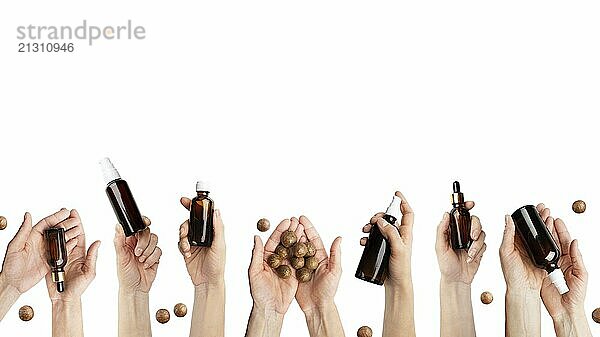 Female caucasian hands hold beauty cosmetisc products and macadamia nuts on white background