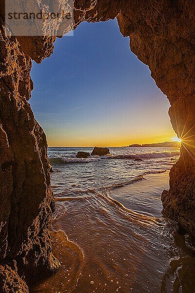 View from the beach through a rock formation to the Atlantic Ocean  sunset on the Algarve coast  Portugal  Europe