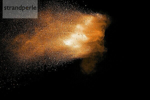 Orange color powder explosion on black background. Orange particles splash