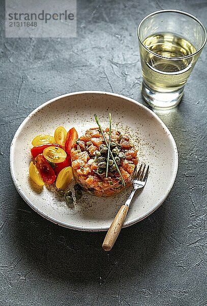 Food  Food  SALMON TARTAR with capers and purple onion on white plate  gray background