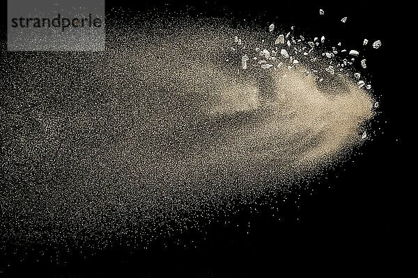 Dry river sand with stone explosion. Golden colored sand splash against black background