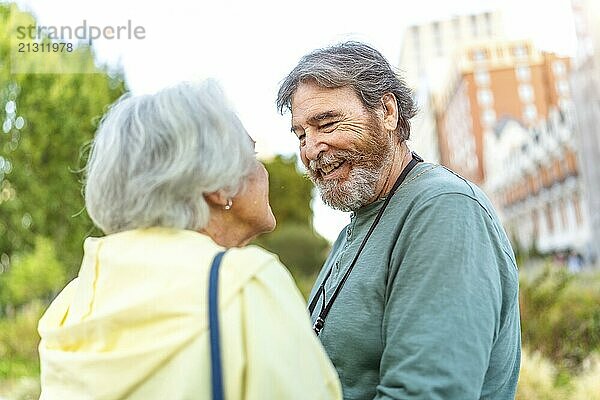 Senior couple looking at each other with tender look standing in an urban park