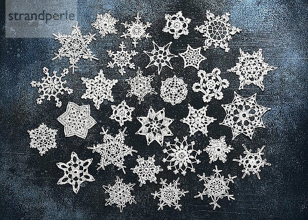 Various crocheted snowflakes on a blue background. Simple  handmade Christmas decoration or small gift. Hobby and handicraft concept