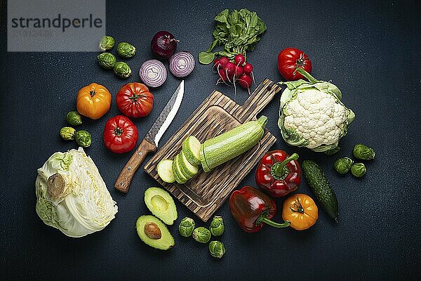 Fresh various vegetables  cut zucchini on wooden cutting board and knife on rustic dark background top view. Cooking vegetarian meal from healthy ingredients  diet food and nutrition concept  food photography  food photography