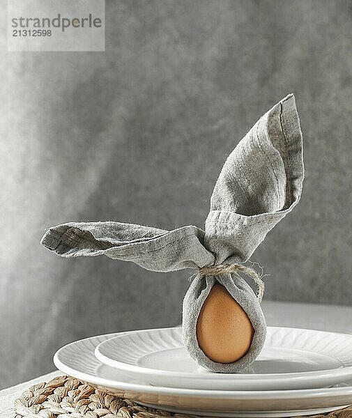 Food  Festive Easter table setting. Funny Easter bunny made of egg and linen napkin on plate. Gray background