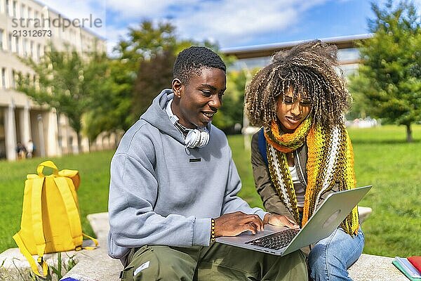 Two multi-ethnic students using laptop sitting outside the campus