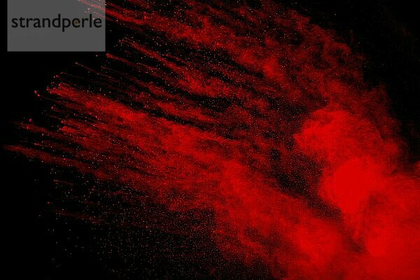 Red powder explosion cloud on black background. Freeze motion of red color dust particles splashing