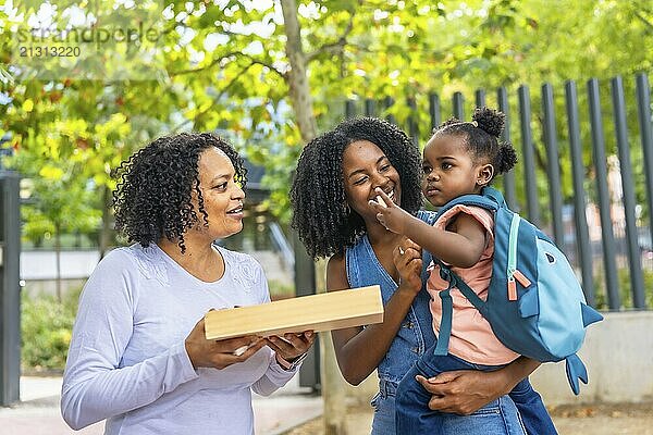 Cute african girl with her mother and grandmother in the park after school day