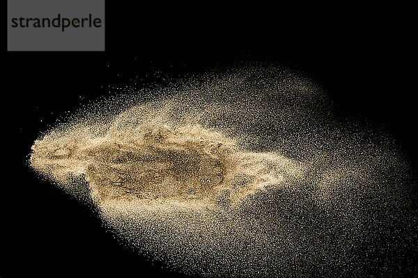 Dry river sand explosion. Golden colored sand splash against black background