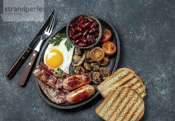 Food  Full fry up English breakfast with fried eggs  sausages  bacon  black pudding  beans  toast and coffee  dark background