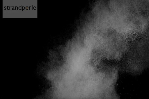 Freeze motion of white dust particles on black background. White powder explosion