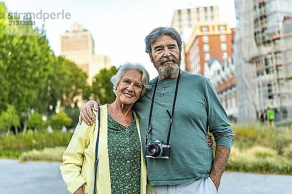 Portrait of senior couple of tourists standing embracing from shoulder in the city