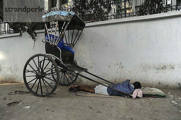 25.02.2011  Kolkata  West Bengal  India  Asia  A rickshaw driver sleeps next to his wooden rickshaw on a roadside in Kolkata  the only city in India where hand-pulled rickshaws still exist  Asia