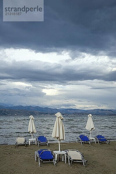 Kalamaki  Corfu  Greece  Sun loungers and parasols on Kalamaki beach in the north-east of the Greek island of Corfu. In the background mainland Albania with the seaside resort of Saranda  Europe