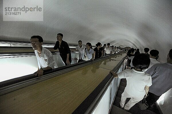 09.08.2012  Pyongyang  North Korea  Asia  Commuters on an escalator leading to an underground station in Pyongyang that is accessible to Western visitors. Some of the escalators go more than one hundred metres underground and serve as bunkers in the event of war  Asia