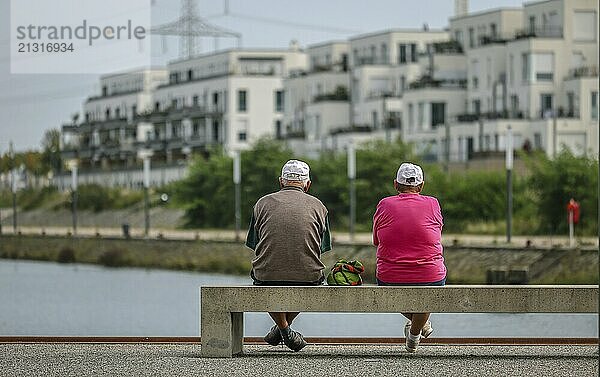 Gelsenkirchen  North Rhine-Westphalia  Germany  Senior citizens sitting on a park bench at the marina in the new Graf Bismarck city quarter  new-build flat block  site of the former Graf Bismarck colliery  on the Rhine-Herne Canal in the Gelsenkirchen Bismarck district  Europe