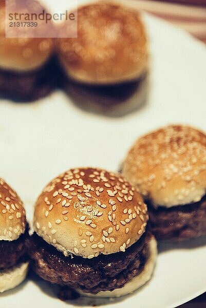 Homemade beef mini burgers on white plate. Close up