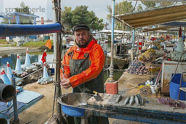 Fishermen standing in the harbour  dressed in orange  ready to sell fish  busy atmosphere at the pier  Nea Kios  Argolis  Peloponnese  Greece  Europe