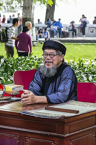 HANOI  VIETNAM  NOVEMBER 14: Old vietnamese man in national dress writes hieroglyphs on old paper at the street at November 13  2016 in Hanoi  Vietnam  Asia