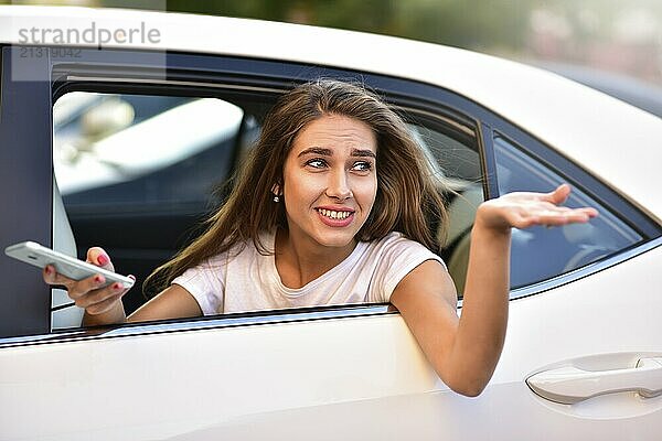 Beautiful woman with phone smiling while sitting on the back seat in the car