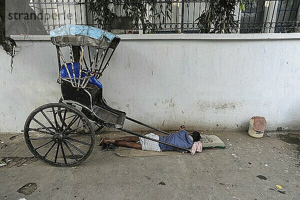 25.02.2011  Kolkata  West Bengal  India  Asia  A rickshaw driver sleeps next to his wooden rickshaw on a roadside in Kolkata  the only city in India where hand-pulled rickshaws still exist  Asia