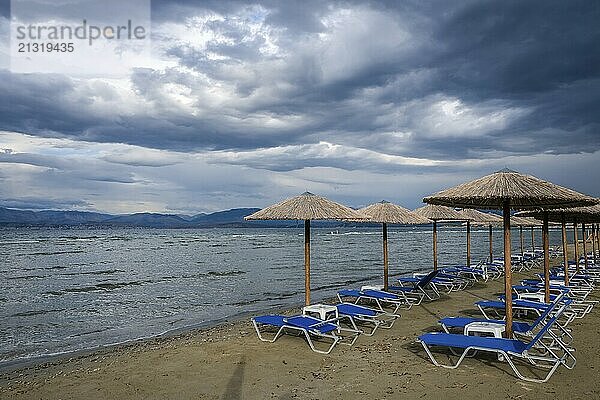 Kalamaki  Corfu  Greece  Sun loungers and parasols on Kalamaki beach in the north-east of the Greek island of Corfu. In the background mainland Albania with the seaside resort of Saranda  Europe