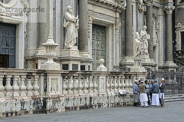 A group of Muslim men on the Piazza Duomo in front of the Roman Catholic Cathedral dedicated to Saint Agatha  Catania  Sicily  Italy  Europe