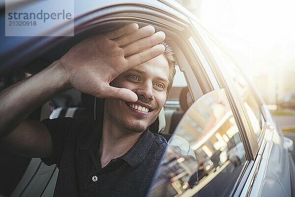 Image of young handsome guy sitting in car and meet someone