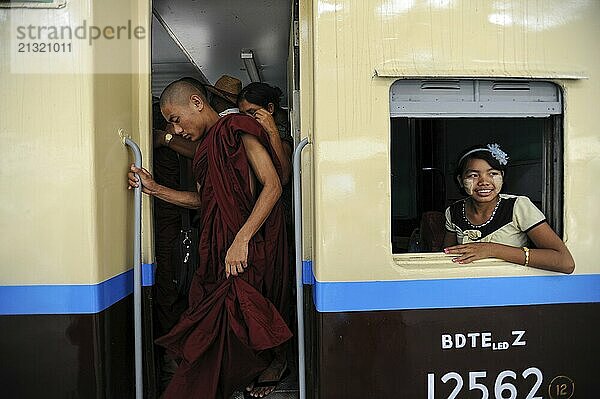 10.04.2014  Yangon  Republic of the Union of Myanmar  Asia  A Buddhist monk and other train travellers get off a train at the main station while a girl looks out of the train window