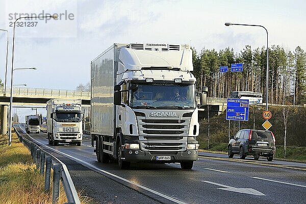 FORSSA  FINLAND  OCTOBER 29  2016: Busy traffic with three white transport trucks  car and bus at intersecting roads on a sunny day in autumn in Forssa  Finland  Europe