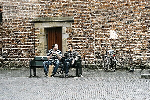 Utrecht  Netherlands  August 4  2016: Two men sitting on a publick bench in historic centre of Utrecht  the Netherlands