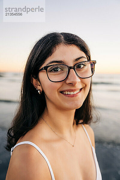 Smiling woman in glasses enjoying a beach at sunset