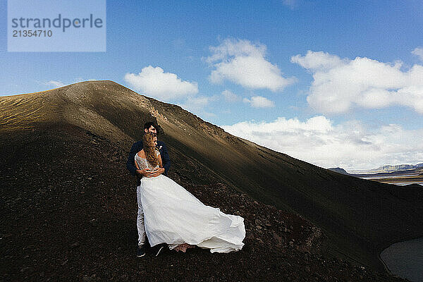 Wedding couple embracing while standing close to the lake in Iceland