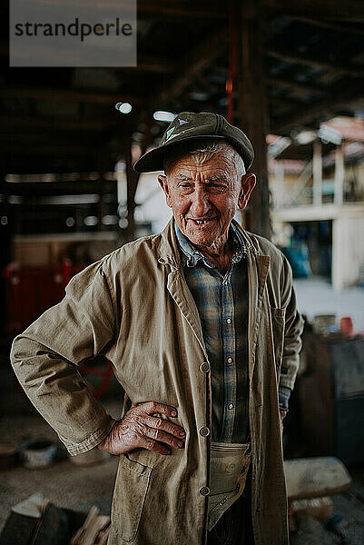 Old man in working clothes standing in his barn.