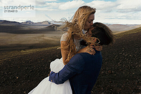 The groom kisses the bride in the mountains of Iceland.