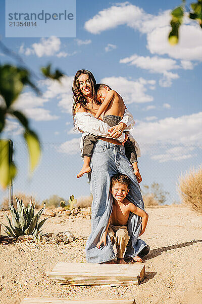 Laughing mother with two boys  one held and the other peeking out