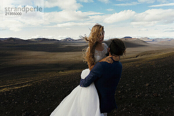 Wedding couple embracing while standing close to the lake in Iceland