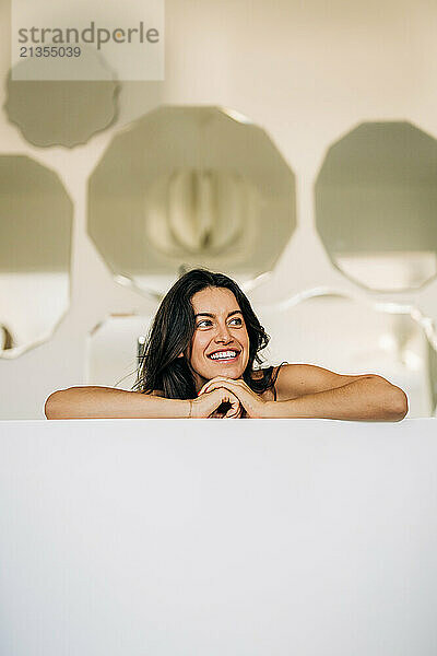 Smiling woman leaning with mirrors in the background