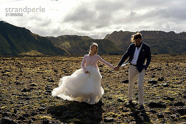 Couple in wedding suits in Iceland against the mountains