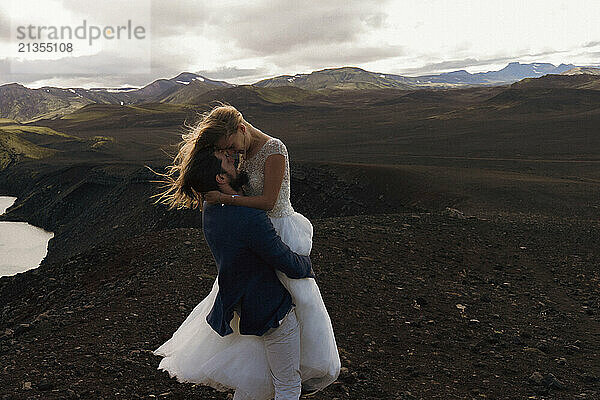 The groom kisses the bride in the mountains of Iceland.