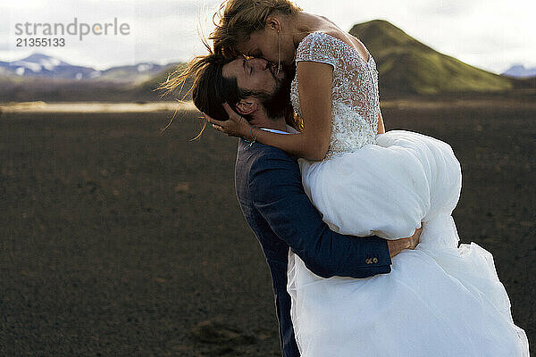 The groom kisses the bride in the mountains of Iceland.