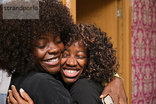 Two smiling black women embracing with afro hairstyle