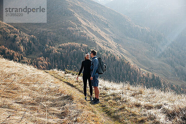 Hiking couple smiling on a scenic mountain trail in Tyrol  Austria