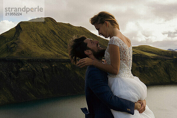 Wedding couple embracing while standing close to the lake in Iceland