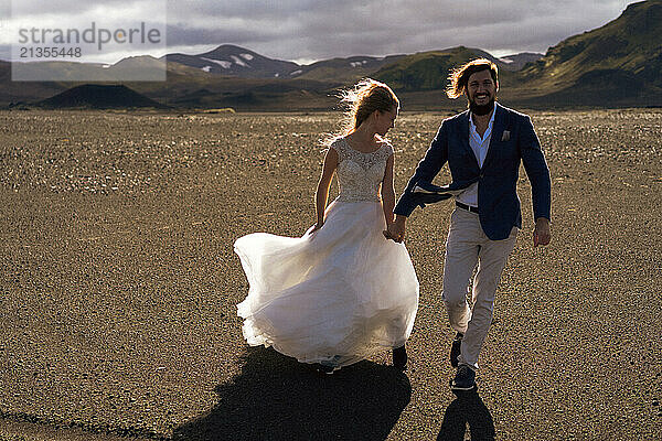 Couple in wedding suits in Iceland against the mountains