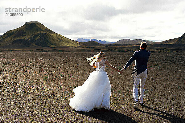 Couple in wedding suits in Iceland against the mountains