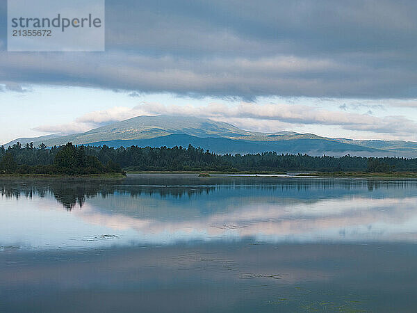 Subtle  first light shines on East Kennebago Mountain  reflected in Flagstaff Lake near Stratton  Maine.